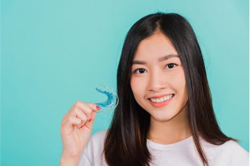 Asian Girl Holding Retainer For Post Treatment Orthodontic Care